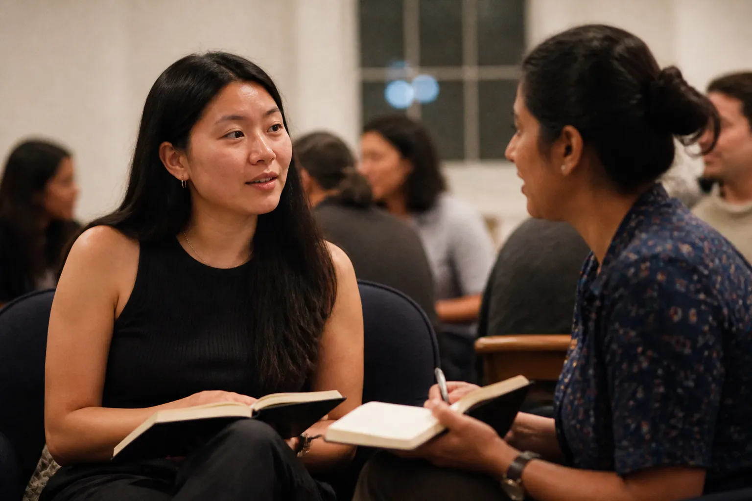 Jennie Choi converses with another woman veteran at a Georgetown meetup with notebooks open at close range.