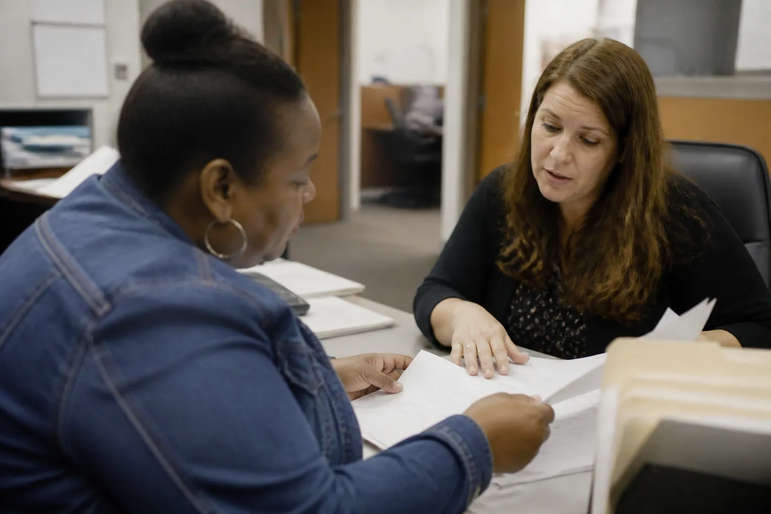 Best housing charities in Omaha: an Omaha renter reviews Section 8 Housing Choice Voucher paperwork with DCHA staff in their office.
