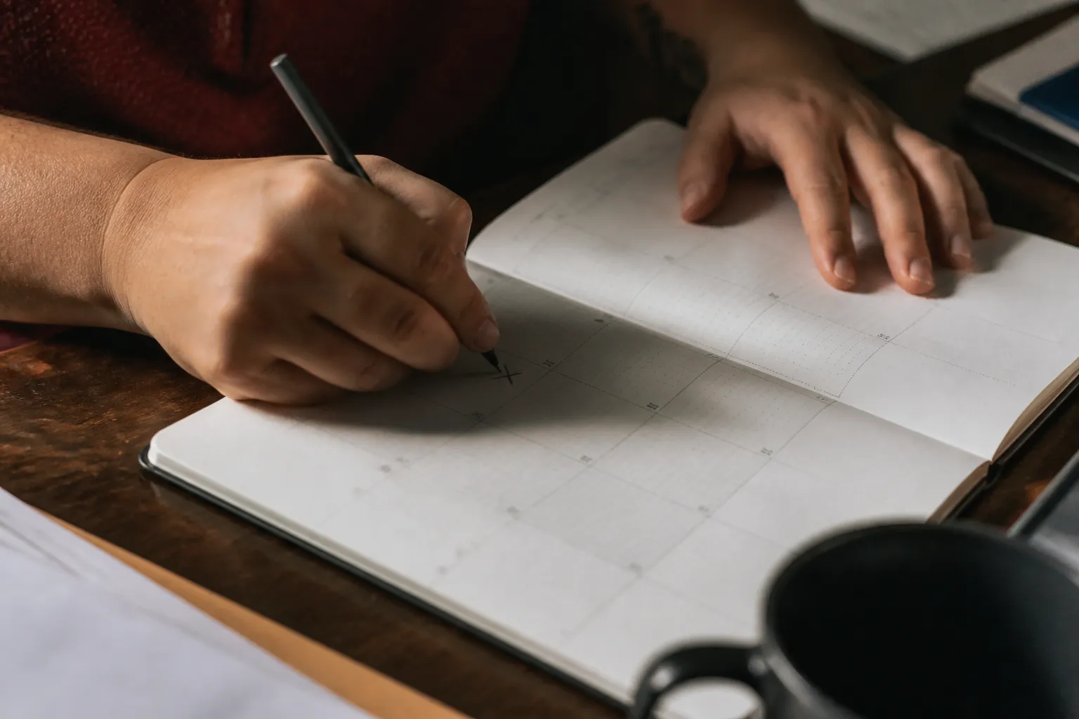 Hand updates a monthly planner in Lincoln, marking rent paid and writing utility due dates for a client.