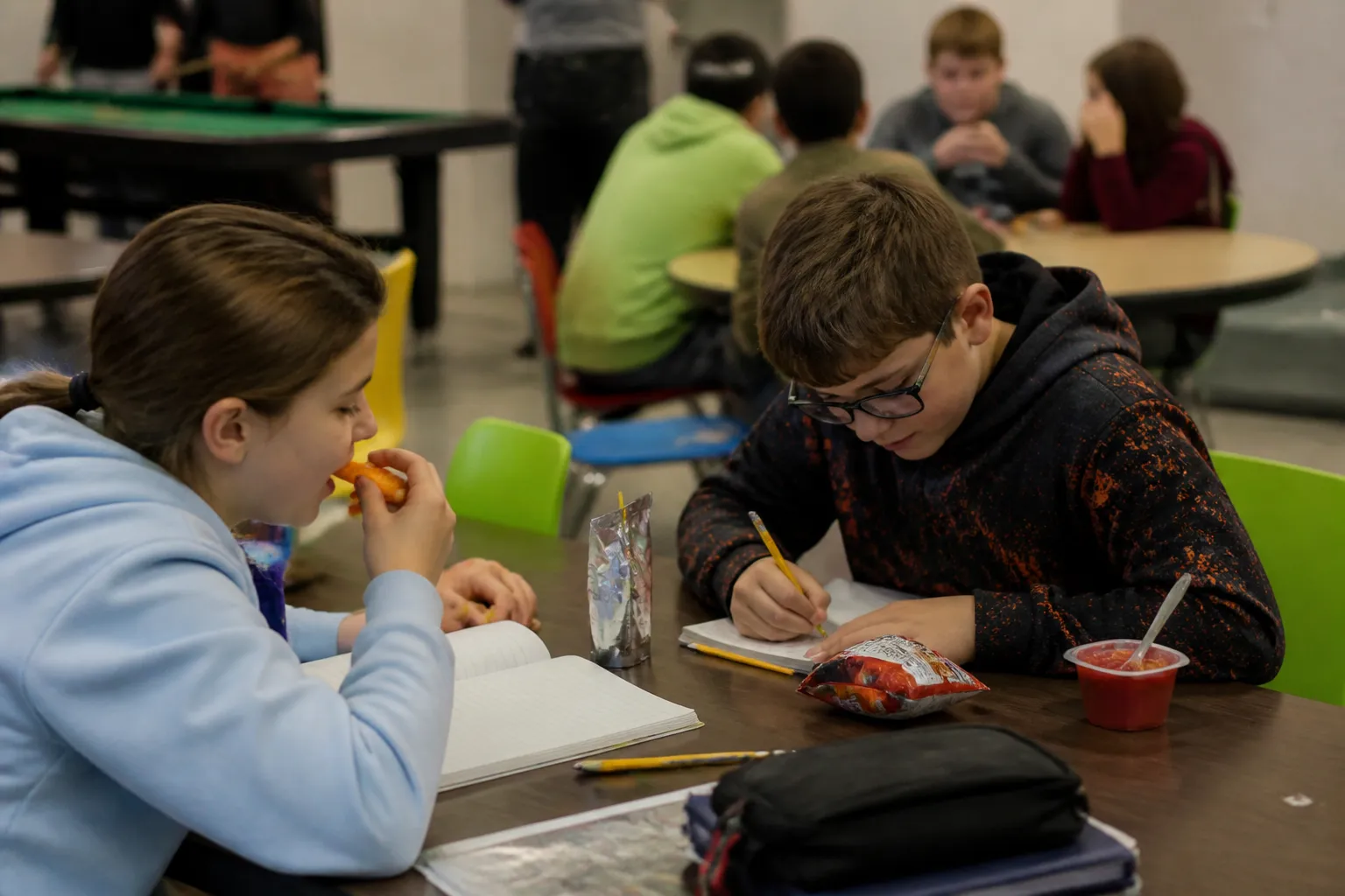 Boys & Girls Club members eat snacks and work on homework at tables in the Clubhouse after school.