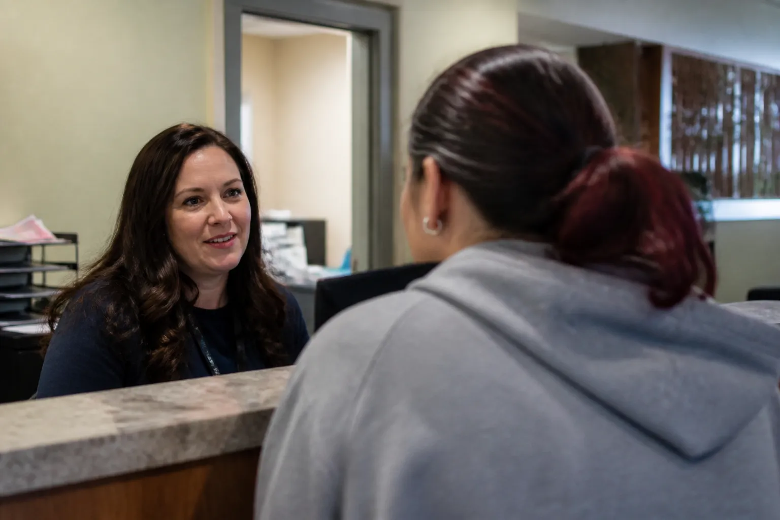 Community Alliance staff member greets a walk-in client at an Omaha behavioral health reception desk.