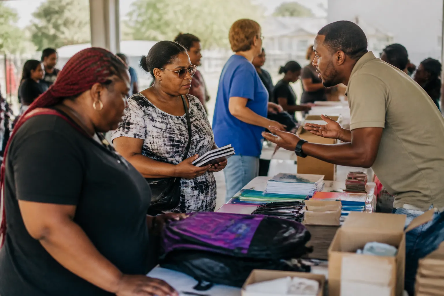 Families and Dallas City Homes staff at a Southern Dallas back-to-school event with supply tables and resources.