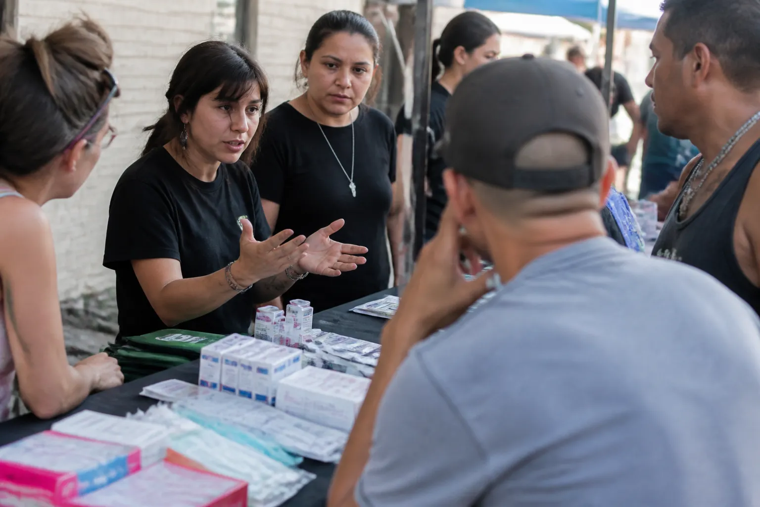 Community members listen as CARE-Dallas staff explain how to donate to harm reduction in Dallas during Narcan pickup and overdose-response training at a Dallas table.