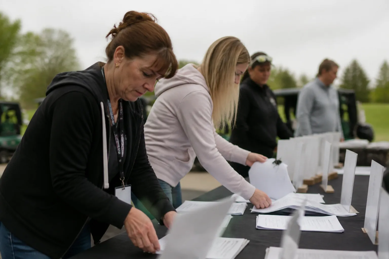 Creating Family Choices golf tournament volunteers sort registration sheets and sponsor signs at a check-in table in Nebraska.