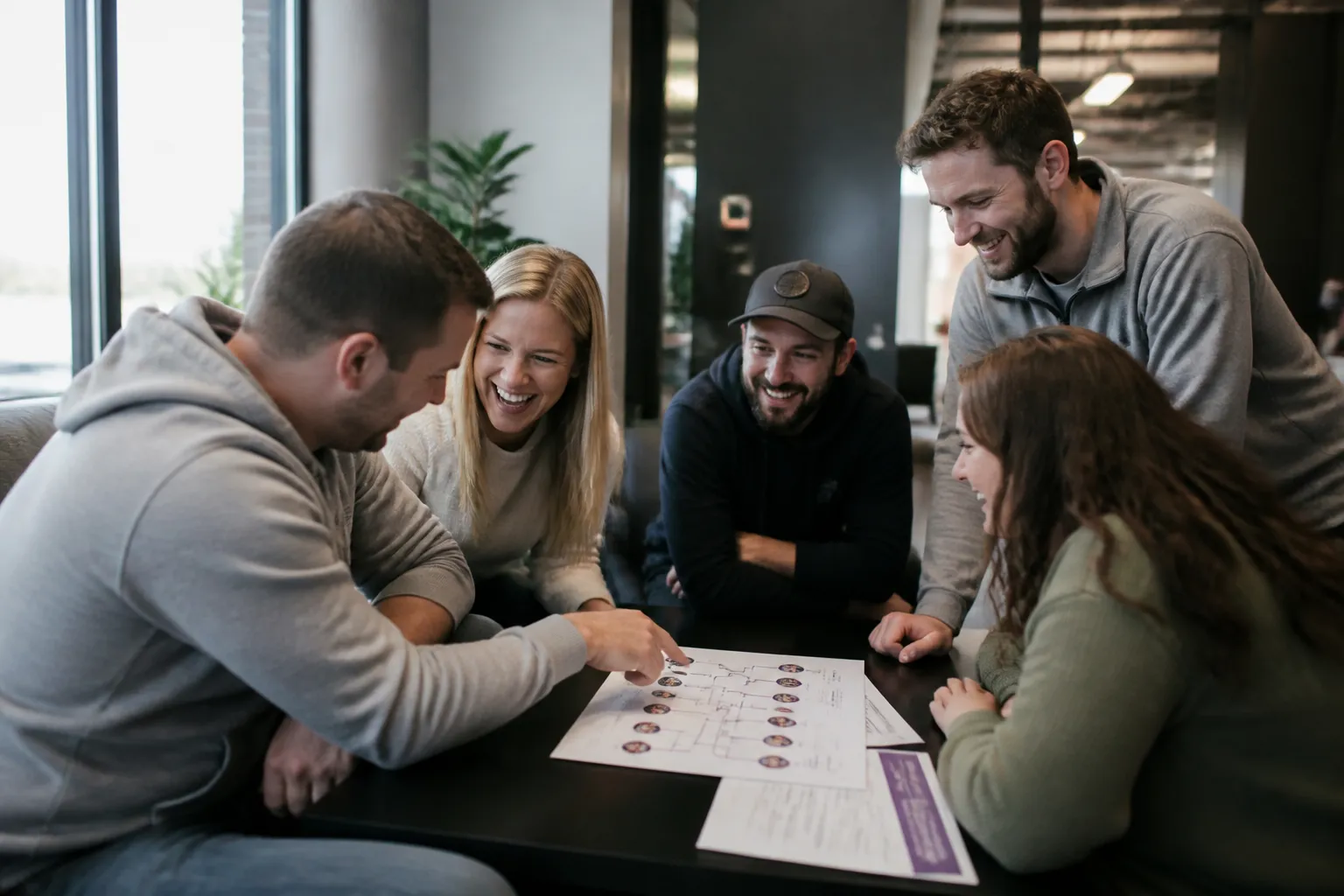 Five Omaha office Growers laugh while reviewing a fundraising bracket for Sexiest Company in America competition.