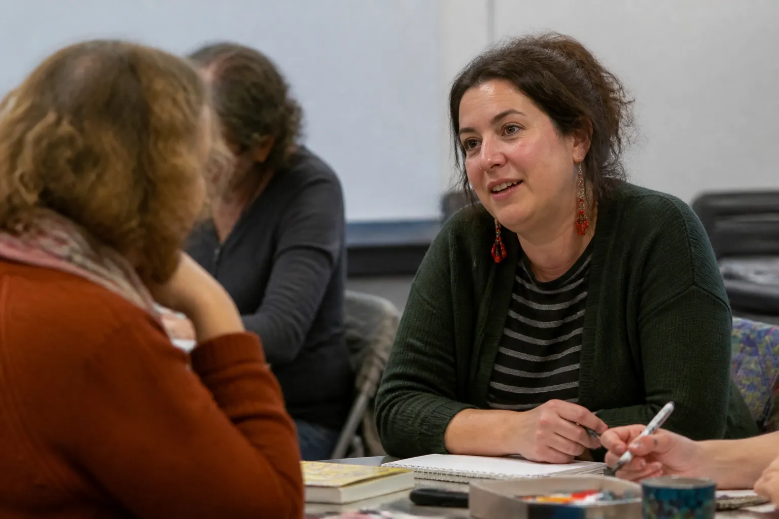 Amber Stewart, a LEVL co-facilitator, talks with participants using notebooks and art supplies in Missoula.