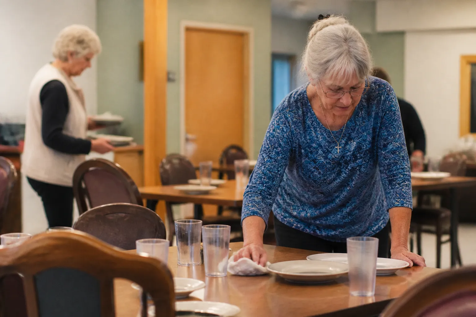 Volunteers set dining tables inside Missoula Senior Citizens Center before daily lunch to support senior services in Missoula, MT.