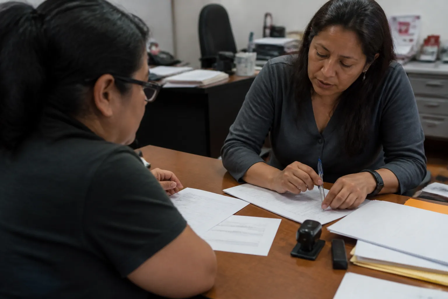 At Centro Aztlan, a resident and advisor review immigration paperwork beside a notary stamp and checklist.