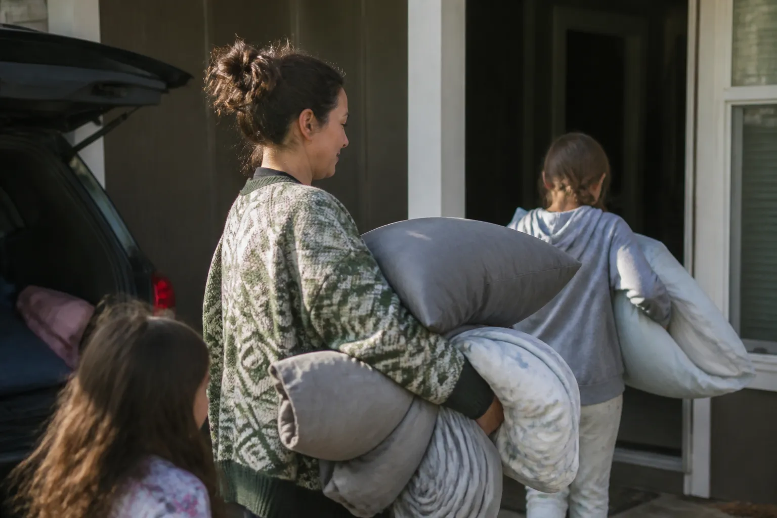 A parent and children bring bedding into a Missoula rental after Rapid Re-Housing help.