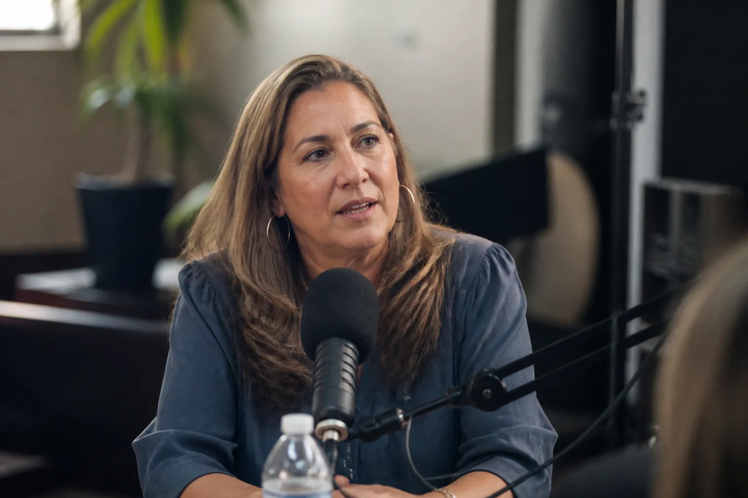 A guest sits at a podcast microphone during a 2025 Sharing is CARE-ing recording for CARE-Dallas.