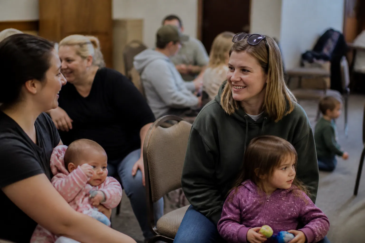 Families and children talk and play seated together during a Ds Connections monthly meeting in Northern Idaho.