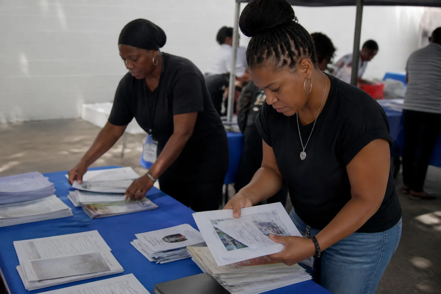 CARE-Dallas staff and volunteers organize outreach materials and training handouts at a Dallas event table.