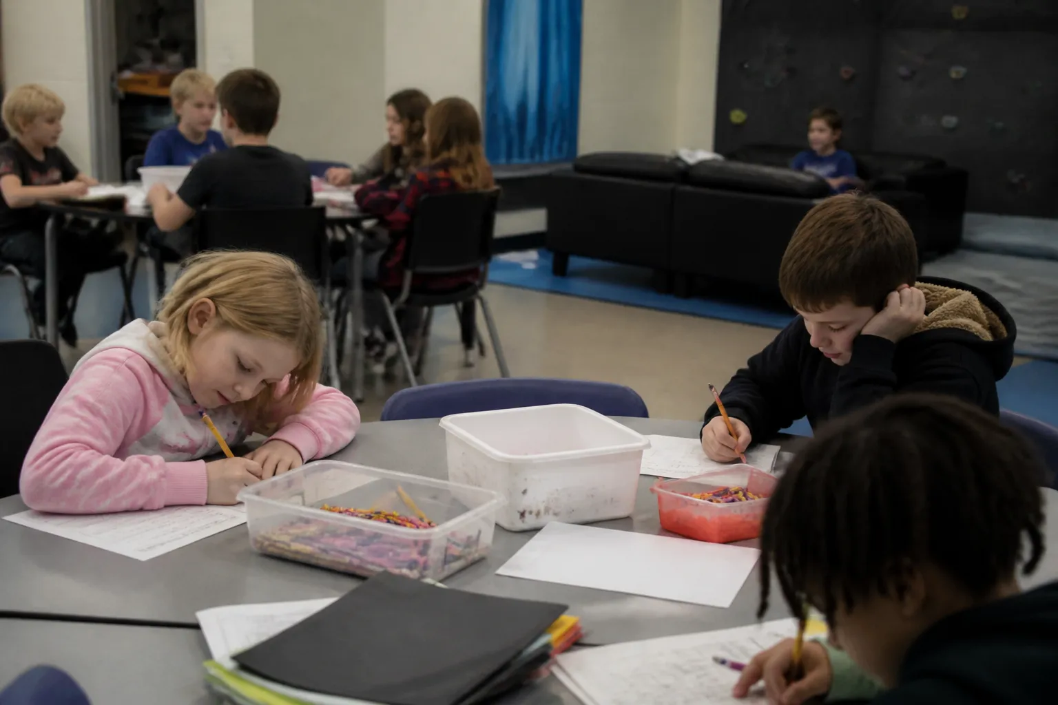 Children at Greater Missoula Family YMCA school-age care complete homework at tables in an indoor room.