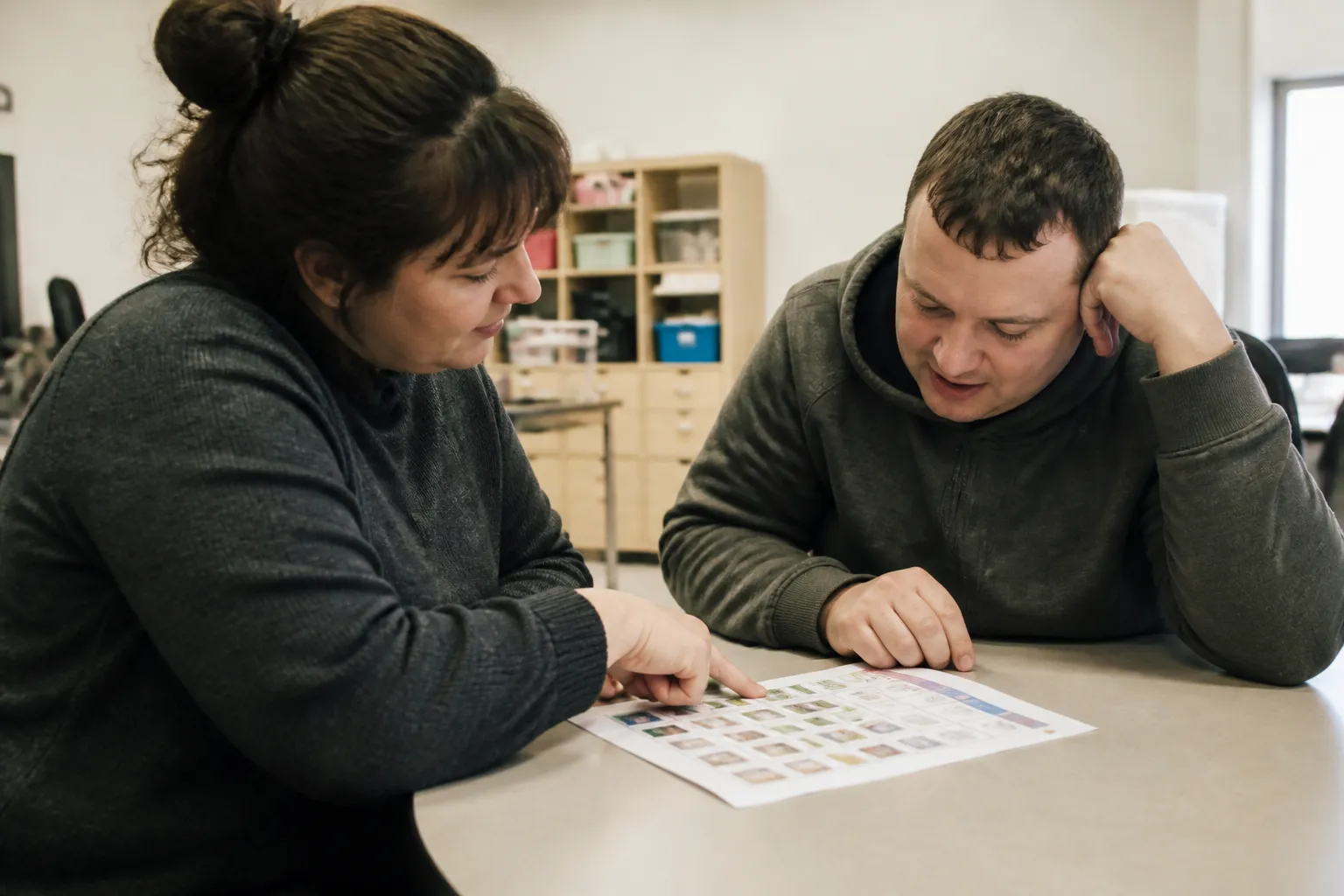 Direct support staff and an adult participant review a daily plan together during intensive habilitation in Missoula.