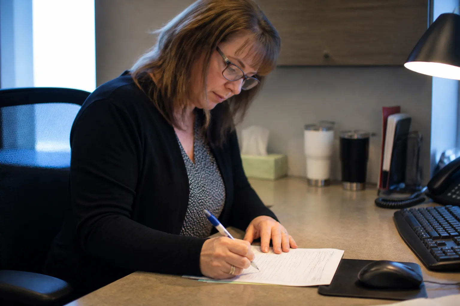 Employee marks a Give Nebraska payroll deduction form designating multiple member nonprofits in a Nebraska office.