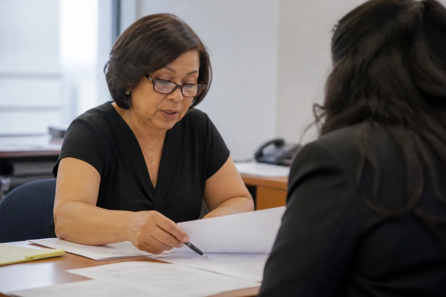 Dress for Success Dallas Career Center volunteer reviews a resume at a desk before a mock interview.