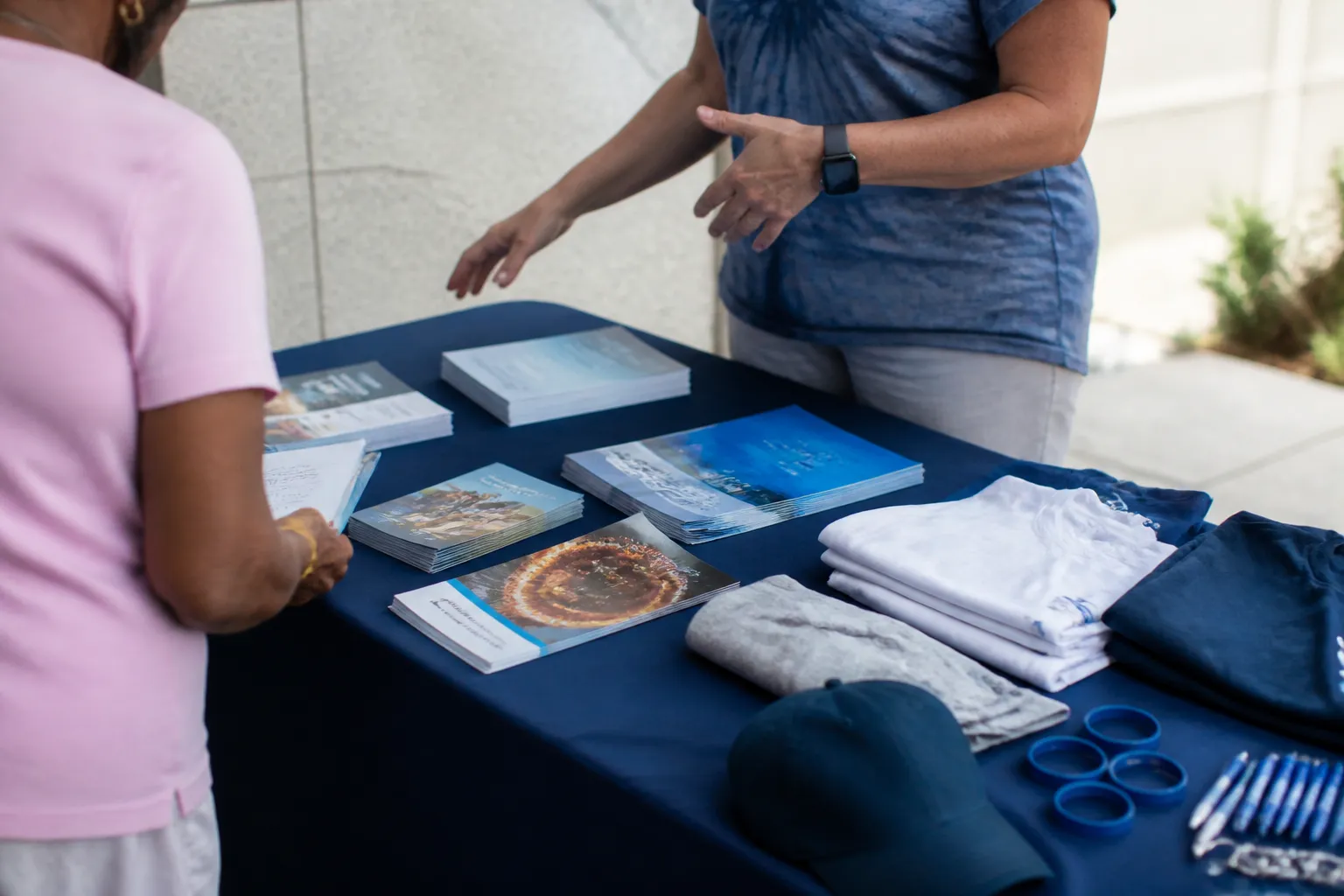 XCancer brochures about clinical trials sit beside awareness apparel on an Omaha outreach table.