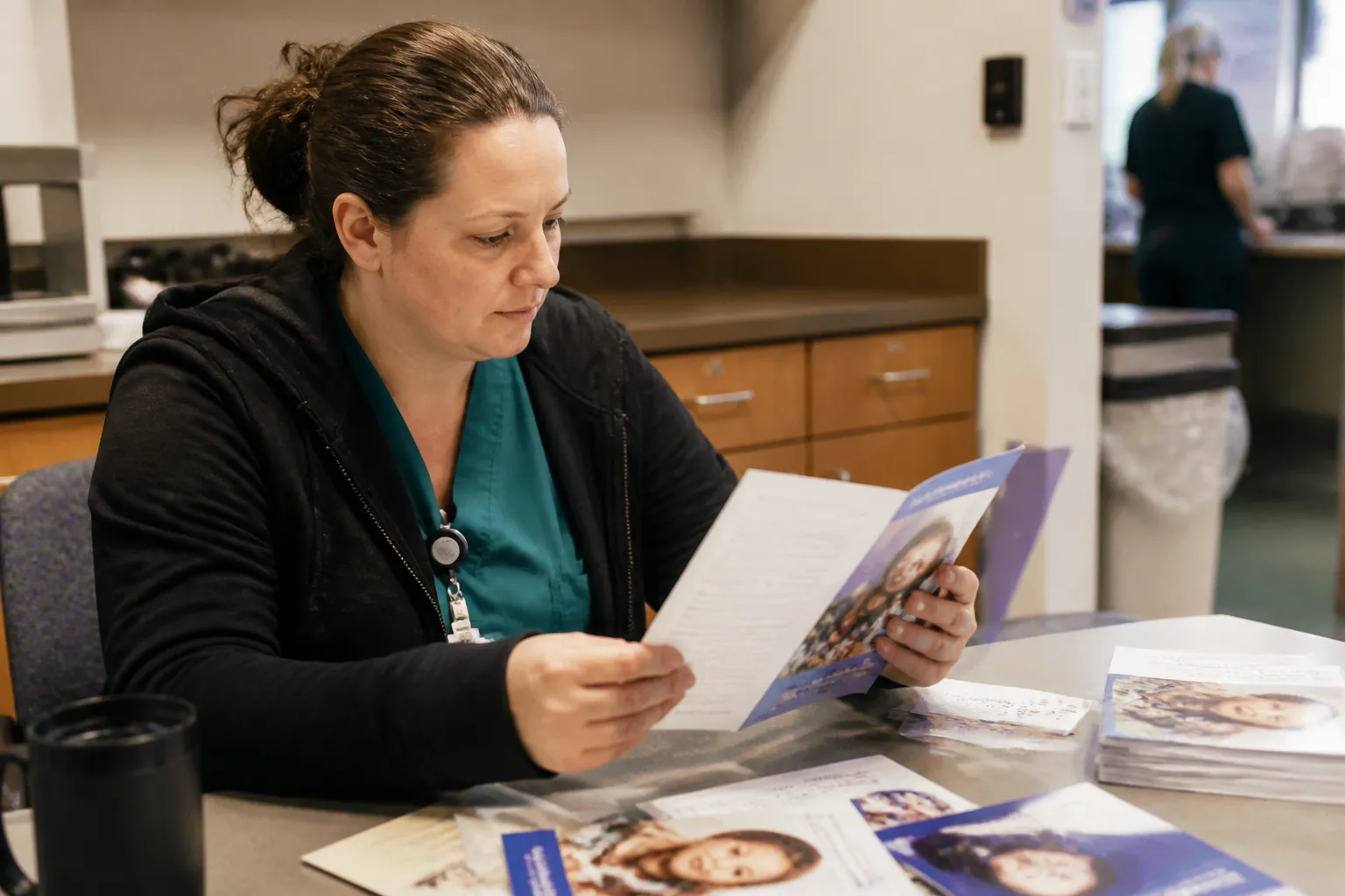 A medical professional reviews Ds Connections Medical Outreach materials in a clinic staff area.